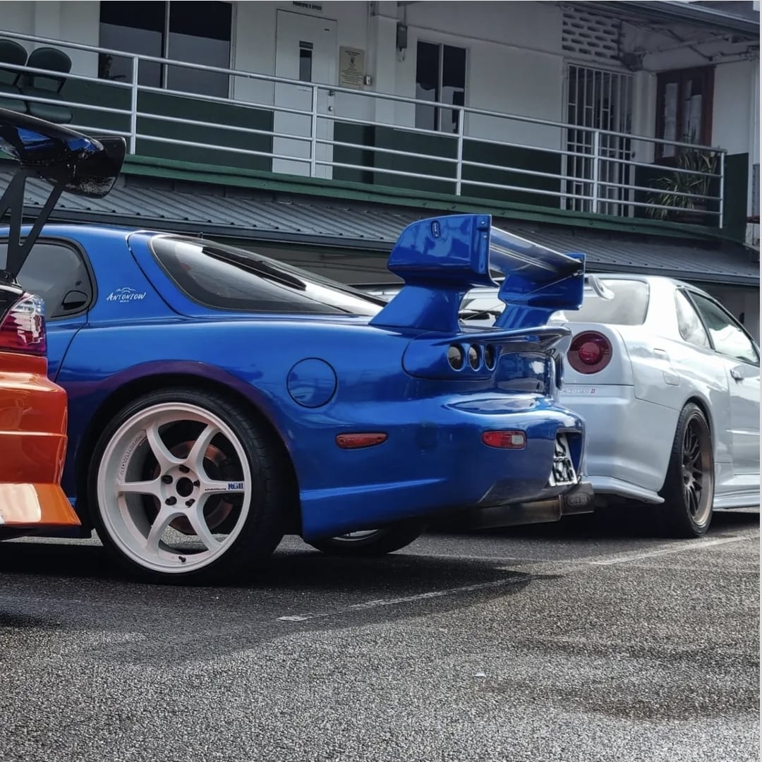 Blue sports car with a rear wing parked beside a silver coupe